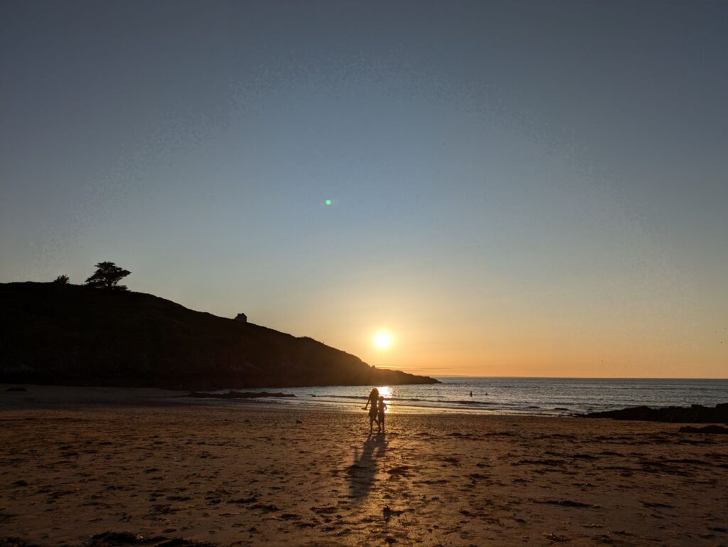 Coucher de soleil sur une plage, enfants jouant au premier plan